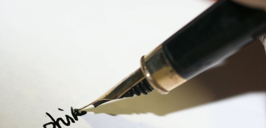 Fountain pen writing cursive letters on white paper