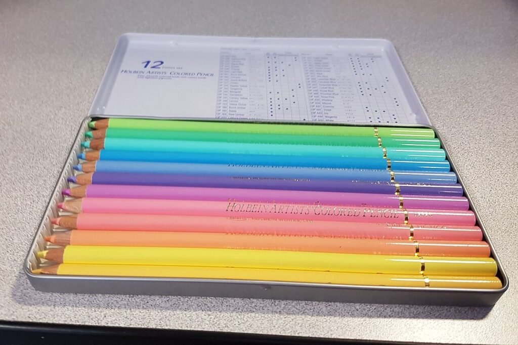 Set of pastel coloured pencils arranged in a tin case