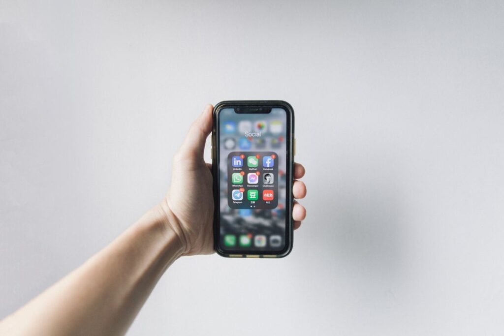 Hand holding a smartphone with social media apps on the screen